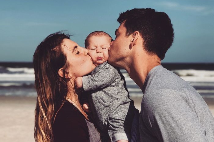 両親からキスをされる赤ちゃん